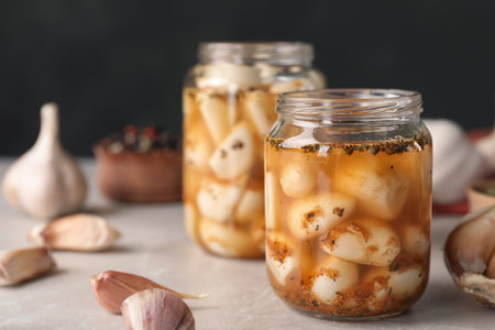 Preserved garlic in glass jar on table, closeup. Space for textの写真素材