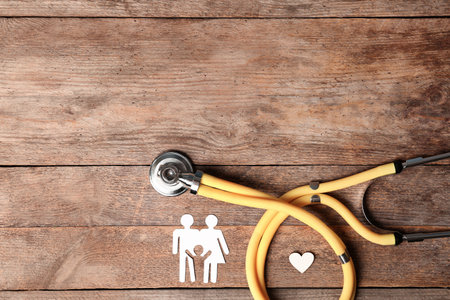 Flat lay composition with heart, stethoscope and paper silhouette of family on wooden background, space for text. life insurance conceptの写真素材