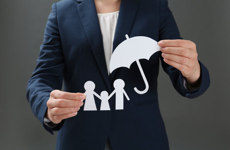 Woman holding cutout paper family and umbrella, closeup. life insurance conceptの写真素材