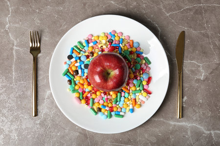 Plate with weight loss pills and apple near cutlery on gray background, flat layの写真素材