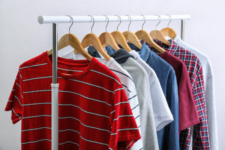 Stylish clothes hanging on wardrobe rack against light backgroundの写真素材