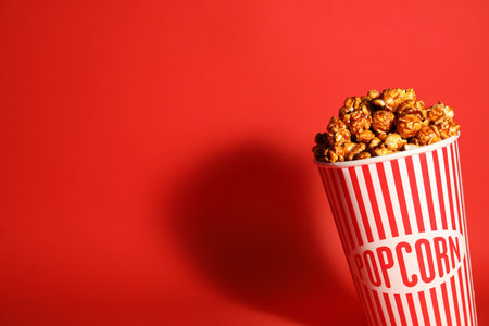 Caramel popcorn in paper cup on color background. Space for textの写真素材
