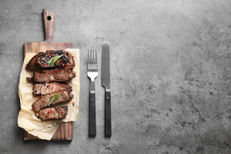 Flat lay composition with delicious barbecued meat served on gray table. Space for textの写真素材