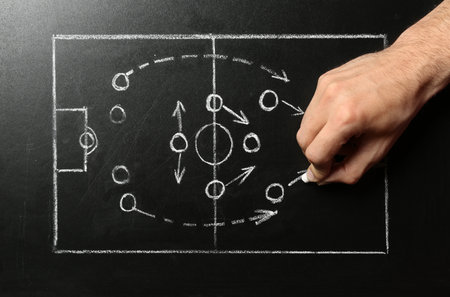 Man drawing football game scheme on chalkboard, top viewの写真素材