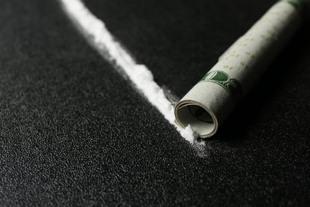Line of cocaine and rolled money bill on dark background, closeupの写真素材