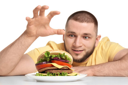 Young man and tasty burger on white backgroundの写真素材