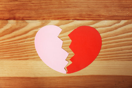 Halves of cut paper heart on wooden background, top view. relationship problemsの写真素材