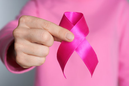 Woman holding pink ribbon on gray background, closeup. breast cancer awarenessの写真素材