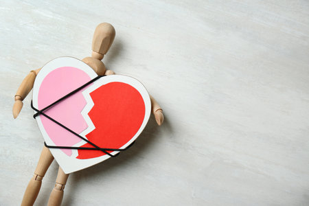 Wooden puppet with symbol of broken heart on gray background, space for text. relationship problemsの写真素材