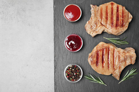 Flat lay composition with grilled meat on slate plate, space for textの写真素材