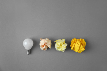 Flat lay composition with lamp bulb and crumpled paper on gray backgroundの写真素材