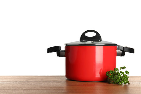 Clean red saucepan and parsley on table against white background, space for textの写真素材