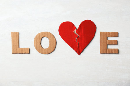 Word "Love" with torn cardboard heart and letters on light background, top view. relationship problemsの写真素材