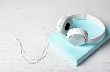 Modern headphones with hardcover book on wooden background. Space for textの写真素材
