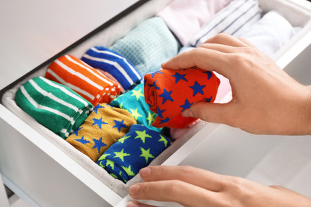 Woman putting color socks into open drawer, closeupの写真素材