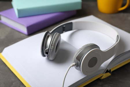 Modern headphones with hardcover book on gray table, closeupの写真素材