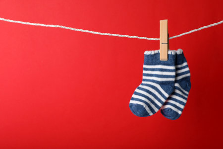 Cute child socks on laundry line against color background. Space for textの写真素材
