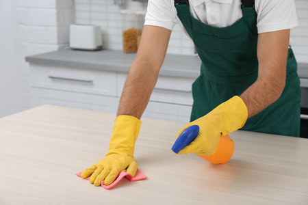 Male janitor cleaning table with rag in kitchen, closeupの写真素材