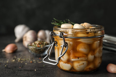 Preserved garlic in glass jar on table, closeup. Space for textの写真素材