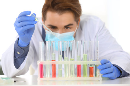 Male scientist working in laboratory, focus on rack with test tubes. Research and analysis