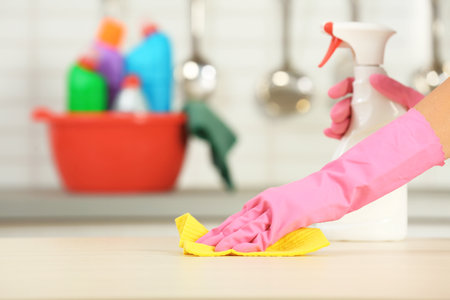 Woman cleaning table with rag in kitchen, closeup. Space for textの写真素材