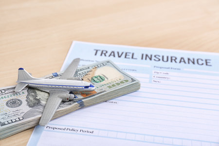 Composition with toy plane, money and travel insurance form on tableの写真素材