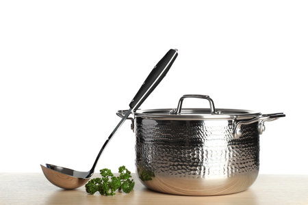New clean sauce pan and ladle on table against white backgroundの写真素材