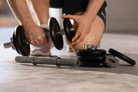 Male athlete with adjustable dumbbells indoors. sports equipmentの写真素材