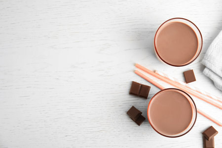 Flat lay composition with glasses of tasty chocolate milk and space for text on wooden background. Dairy drinkの写真素材