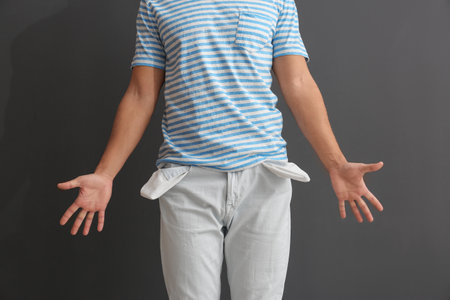 Man showing empty pockets on gray background, closeupの写真素材