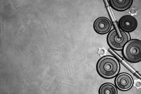 Flat lay composition with dumbbell parts and space for text on stone surfaceの写真素材