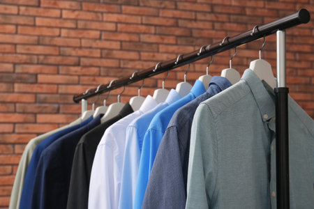 Wardrobe rack with stylish clothes near brick wallの写真素材
