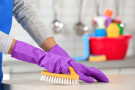 Woman cleaning table with brush in kitchen, closeupの写真素材