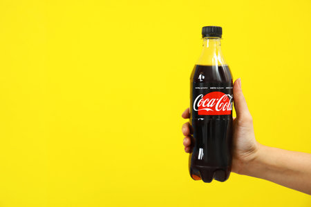 MYKOLAIV, UKRAINE - NOVEMBER 14, 2018: Woman holding bottle of Coca-Cola on color background. Space...