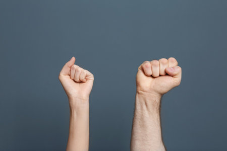 Man and woman showing clenched fists on color backgroundの写真素材