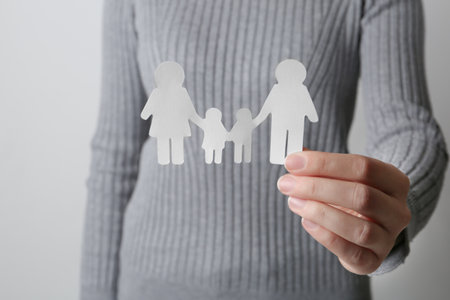 Woman holding paper silhouette of family on gray background, closeup. life insurance conceptの写真素材