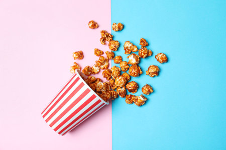 Overturned paper cup with caramel popcorn on color background, top viewの写真素材