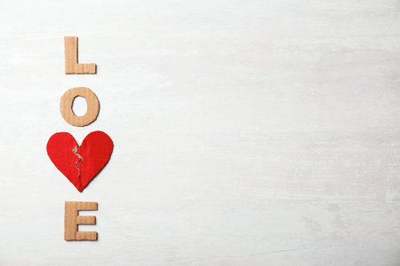 Word "Love" with torn cardboard heart and letters on light background, top view. relationship problemsの写真素材