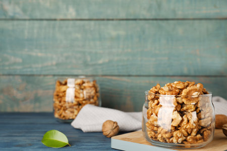 Dishware with walnuts on table against wooden wall. Space for textの写真素材