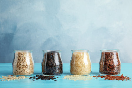 Jars with different types of rice on blue tableの写真素材