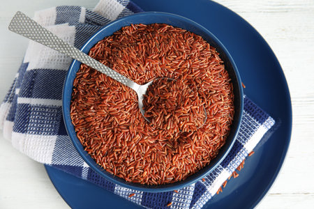 Bowl with uncooked red rice and spoon on white table, top viewの写真素材