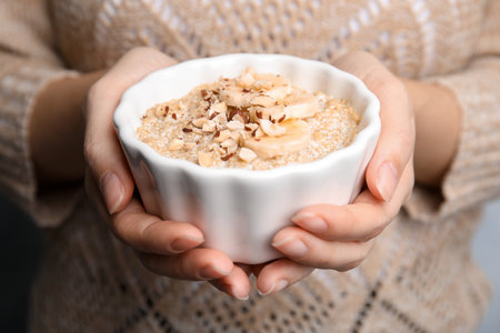 Woman holding bowl of quinoa porridge with banana and nuts, closeupの写真素材
