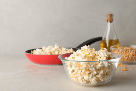 Glass bowl with tasty popcorn on gray table. Space for textの写真素材