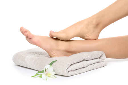 Woman with smooth feet, flower and towel on white background, closeup. spa treatmentの写真素材