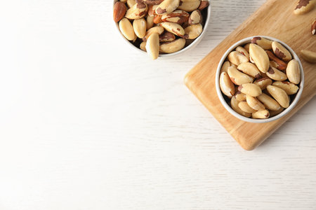 Bowls with tasty Brazil nuts and space for text on white wooden table, top viewの写真素材