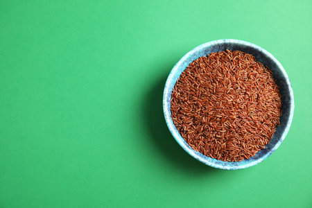 Bowl with uncooked red rice on color background, top view. Space for textの写真素材