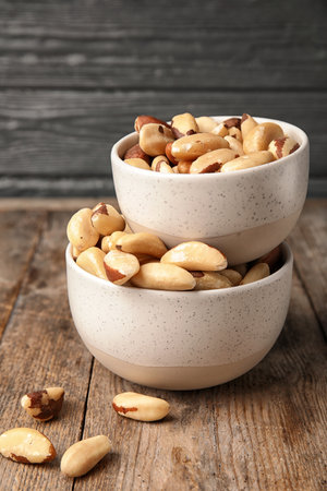 Bowls with tasty Brazil nuts on wooden tableの写真素材
