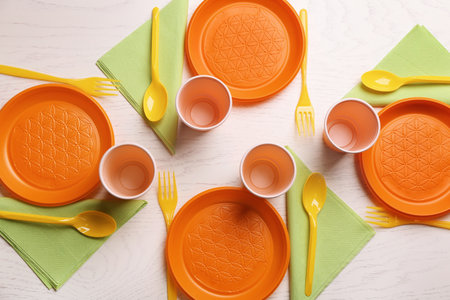 Composition with plastic dishware on wooden background, flat lay. Picnic table settingの写真素材