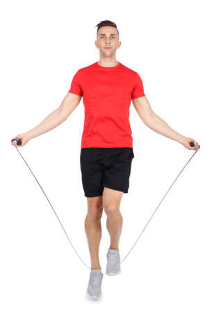 Full length portrait of young sportive man training with jump rope on white backgroundの写真素材