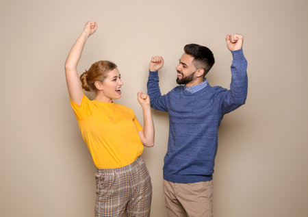 Happy young people celebrating victory on color backgroundの写真素材